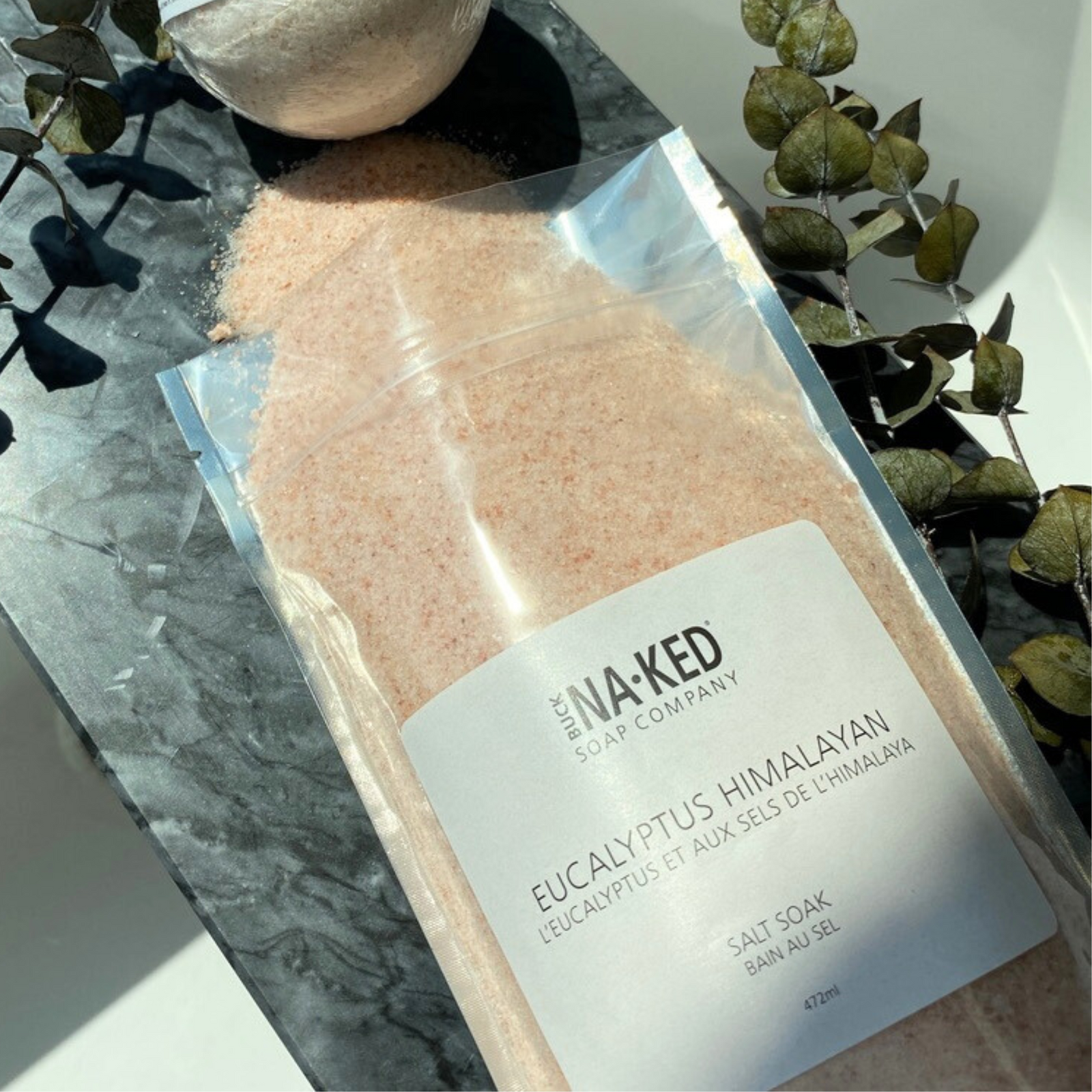 Eucalyptus Himalayan salt soak packaging with 'NA-KED Soap Company' label on a marble surface.