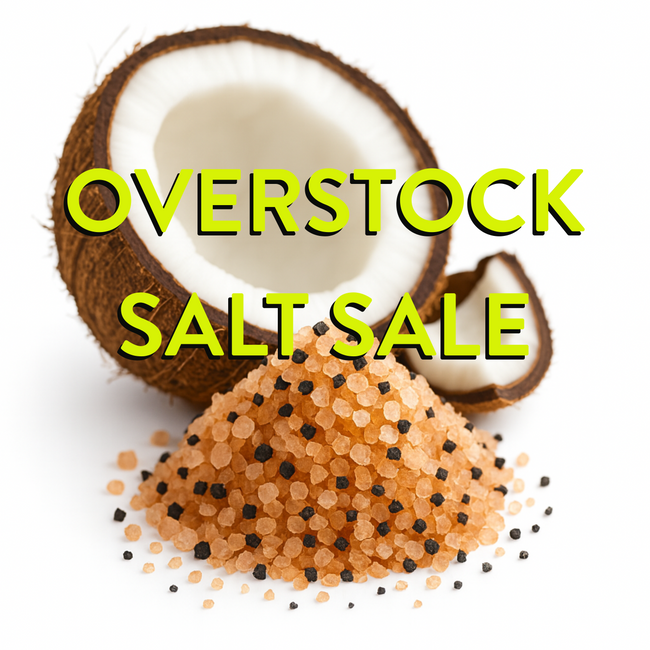 himalayan and black lava salt in a small pile with a halve coconut behind. on white background.